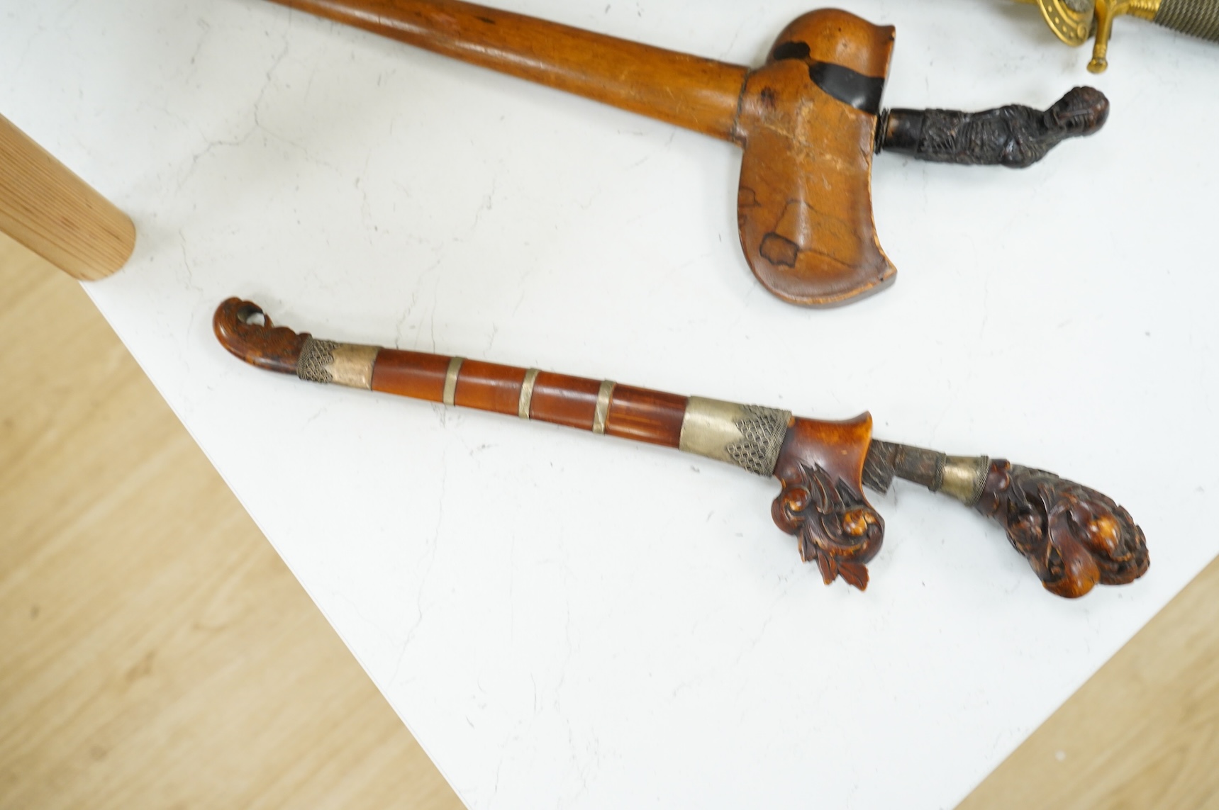 A Javanese dagger kris with straight pamor blade, wooden hilt carved as raksha, in its wooden sheath, together with a decorative dagger bade-bade, with etched blade